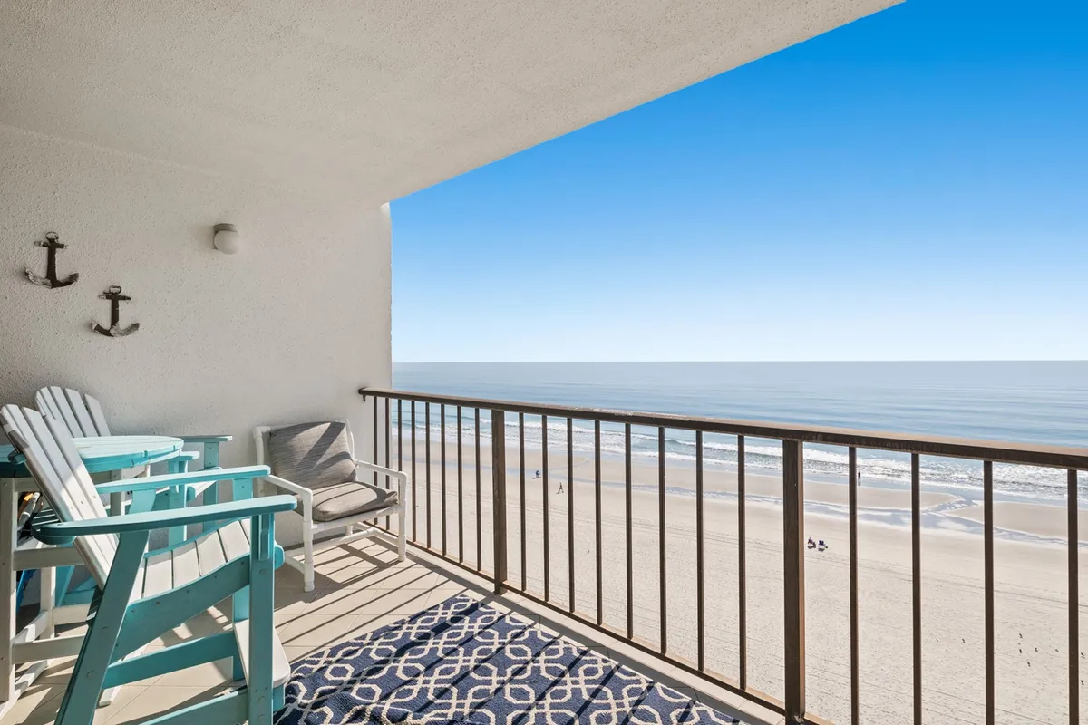 An inviting balcony with outdoor furniture overlooks the sparkling Atlantic, framed by a balcony railing. The tranquil scene is perfect for sipping morning coffee, reading, or enjoying the vibrant colors of sunset over the water.