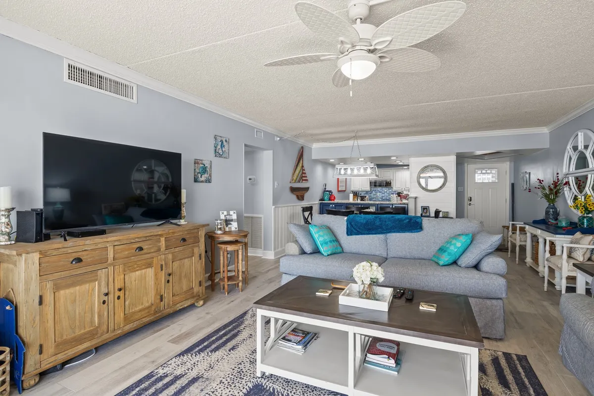 Featuring a plush sofa with cushions, a large flat-screen TV, a wooden sideboard, and a coffee table, this living area exudes a cozy, relaxed atmosphere ideal for movie nights or lively conversations. The setup suggests plenty of room for group activities and comfort.